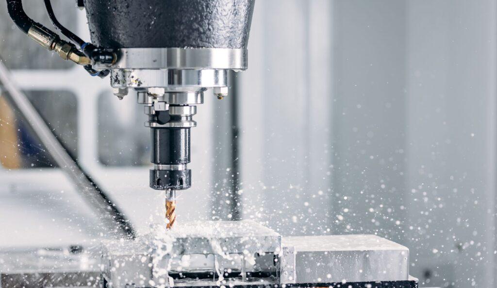 Nahaufnahme einer CNC-Fräsmaschine, die präzise Metallbearbeitung durchführt, mit spritzendem Kühlmittel.