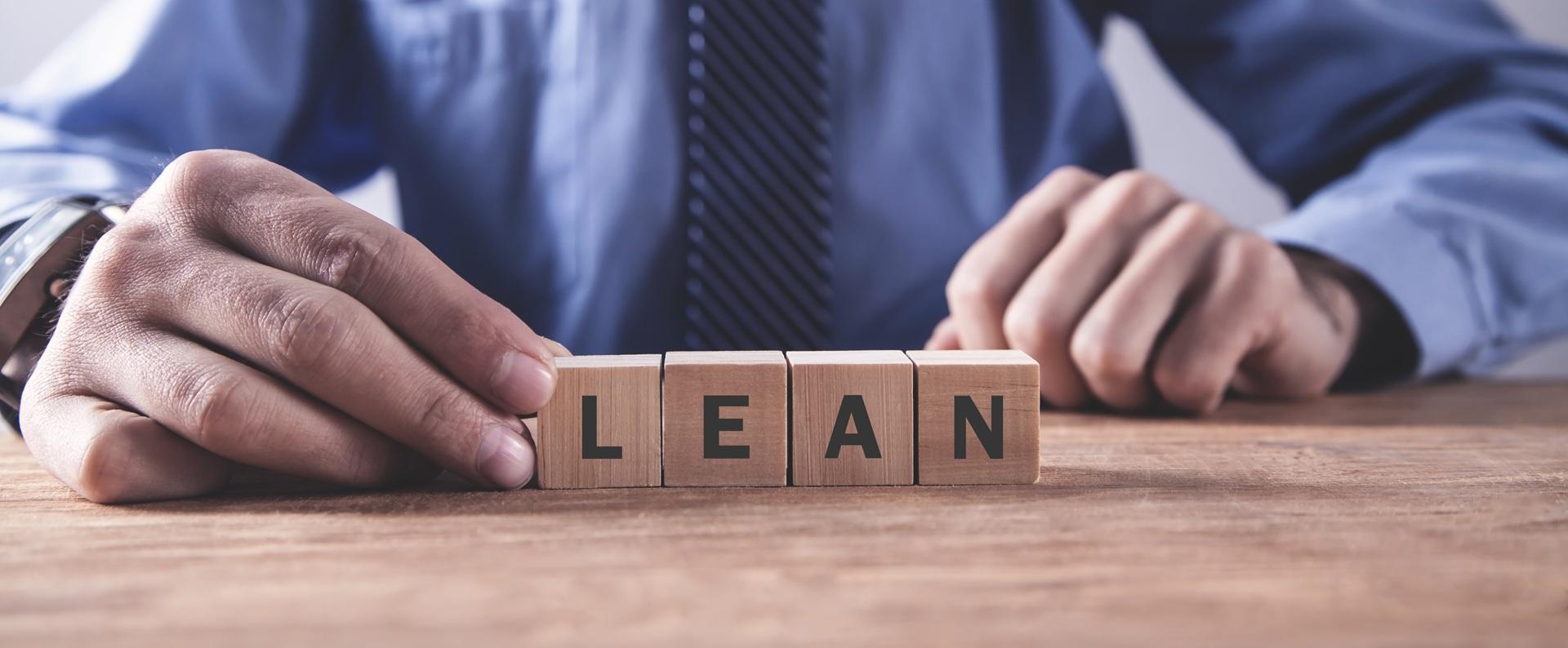 Geschäftsmann hält Holzblöcke mit Lean-Schriftzug | Umreifungsgerät